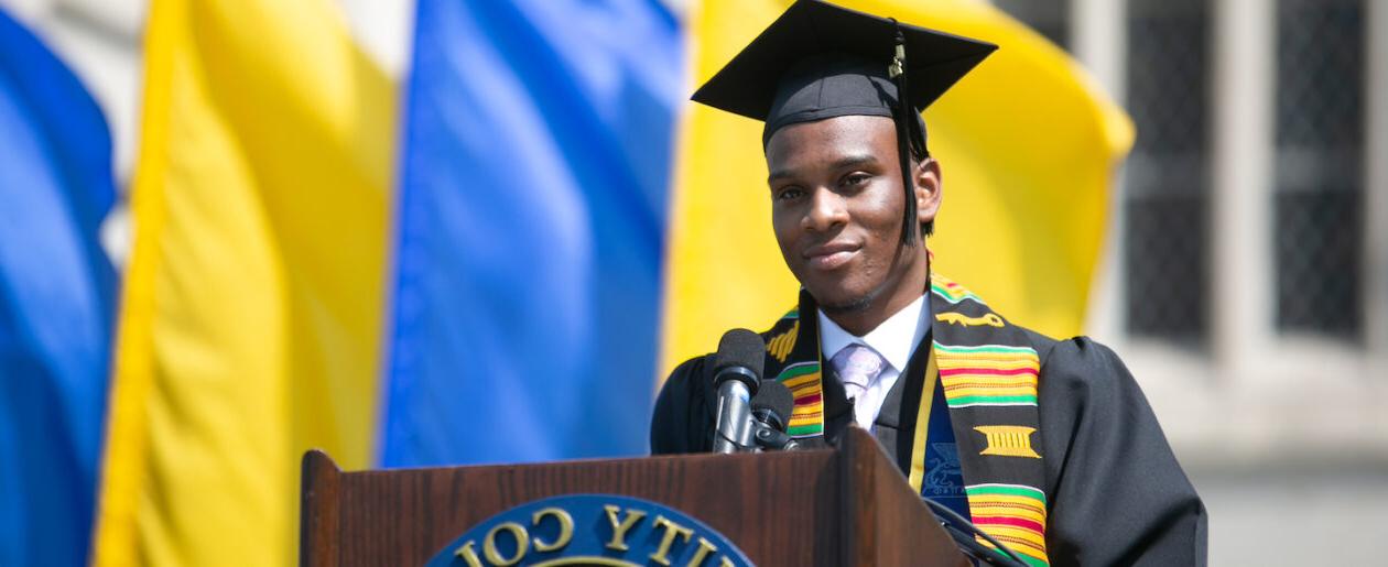 A trinity college grad standing at the graduation podium ready to speak